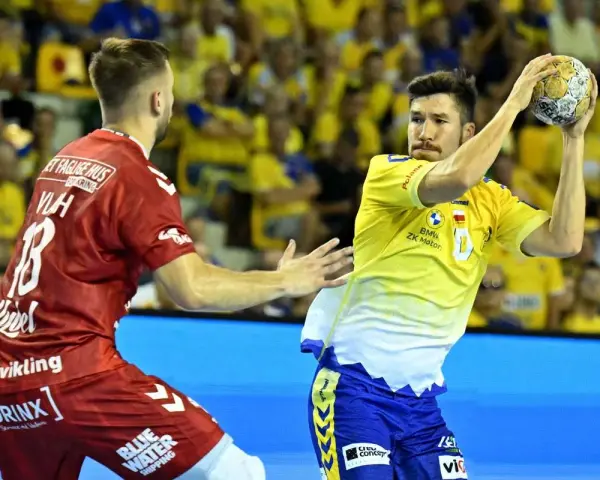 Piłkarz Aalborg Handball w żółtej koszulce rzuca piłkę, obok zawodnik w czerwonej.
