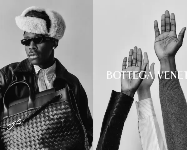 Uomo con cappello di pelliccia e borsa Bottega Veneta, mani alzate. Un omaggio alla storia del brand.