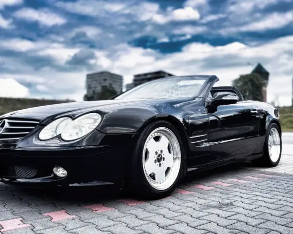 Czarny Mercedes SL R230 na parkingu. Nawet klasyki mają swoje **awarie i problemy**, ale ten wciąż wygląda świetnie.