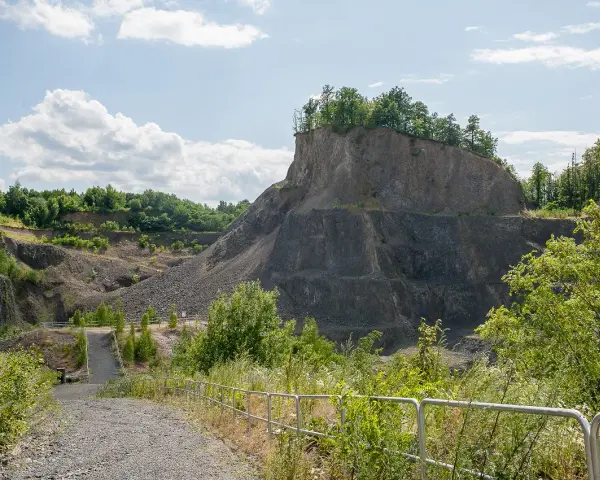 Kamieniołom przypomina wilczą górę, z której wyrasta bujna zieleń. Ścieżka prowadzi w głąb skalistego krajobrazu.