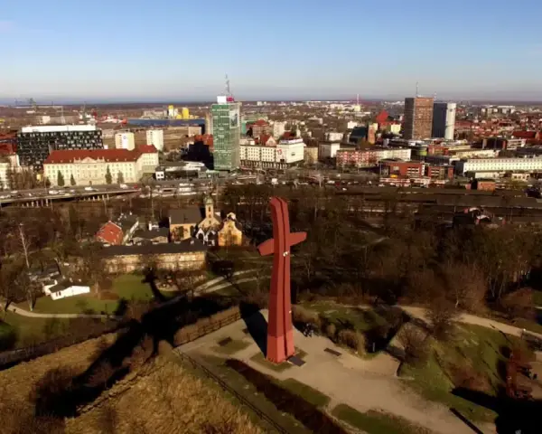 Góra Gradowa z czerwonym monumentem w kształcie krzyża na tle panoramy miasta.