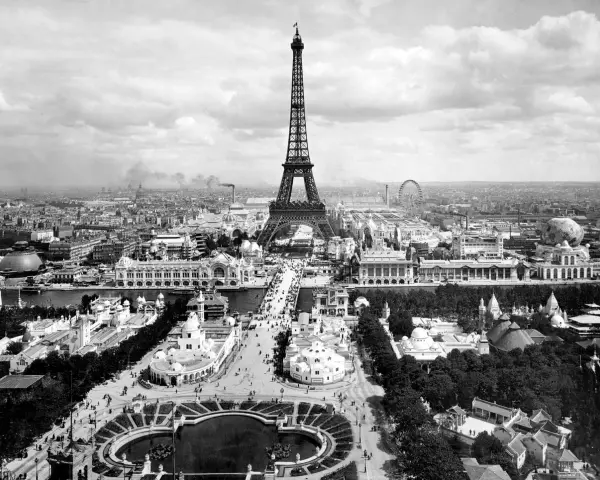 Vista panorámica del **Champ de Mars** con la Torre Eiffel dominando el paisaje, rodeada de pabellones y una noria.