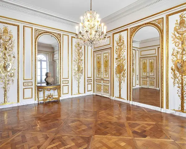 Salón dorado del museo Carnavalet, con suelo de parqué, candelabro de cristal y ornamentación dorada en las paredes.