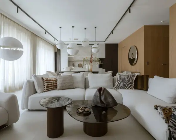 Nowoczesny projekt mieszkania z białą sofą, okrągłymi stolikami i designerskimi lampami.