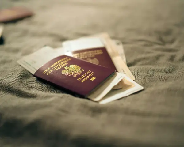 Kilka paszportów leży na szarym materiale. Zastanawiasz się, ile czeka się na paszport w Polsce?