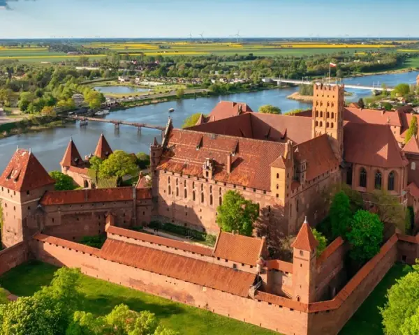 Malbork zamek krzyżacki, potężna twierdza z cegły, góruje nad rzeką Nogat. Otoczony murami, z wieżami i dziedzińcami, zaprasza do odkrywania historii.