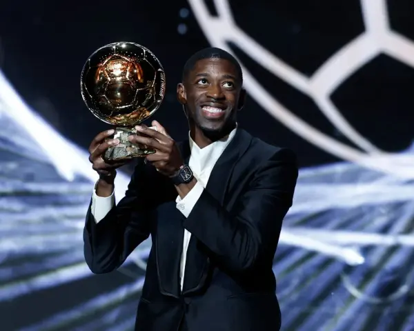 Piłkarz Ousmane Dembélé trzyma Złotą Piłkę na scenie.