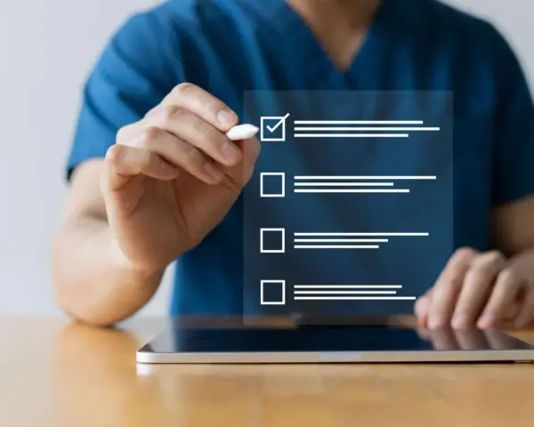 Dłoń zaznacza ptaszkiem pierwszy element na liście kontrolnej wyświetlanej na ekranie tabletu.