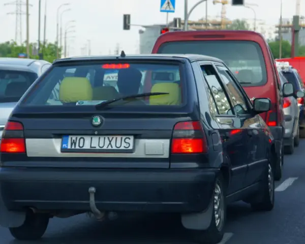 Czarny samochód z indywidualnymi tablicami rejestracyjnymi "WO LUXUS" w korku ulicznym.