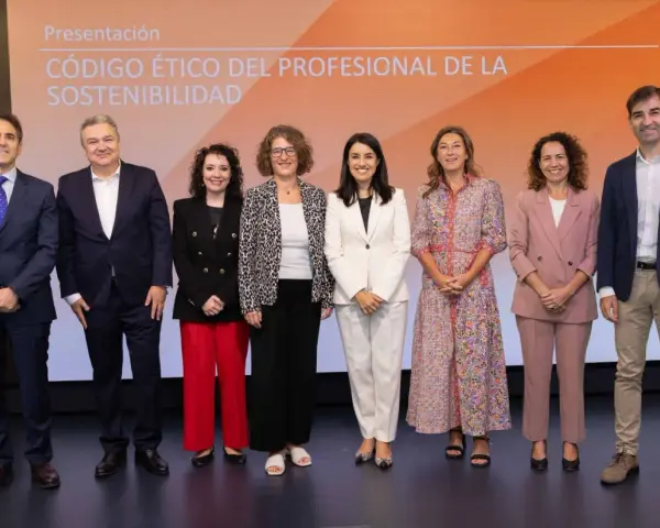Presentación del código de ética de una empresa. Un grupo de siete profesionales posa en un escenario con un fondo naranja y blanco.