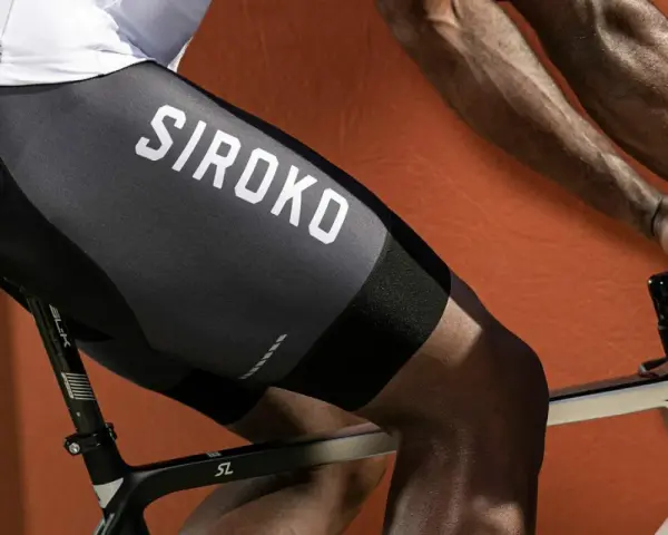 En cyklist med synliga cykling muskler på benen, klädd i svarta cykelbyxor med texten "SIROKO".
