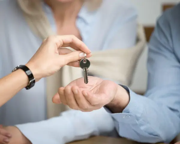 Una mano entrega una llave a otra, simbolizando el inicio de un nuevo hogar. Considera qué tener en cuenta al alquilar un piso.