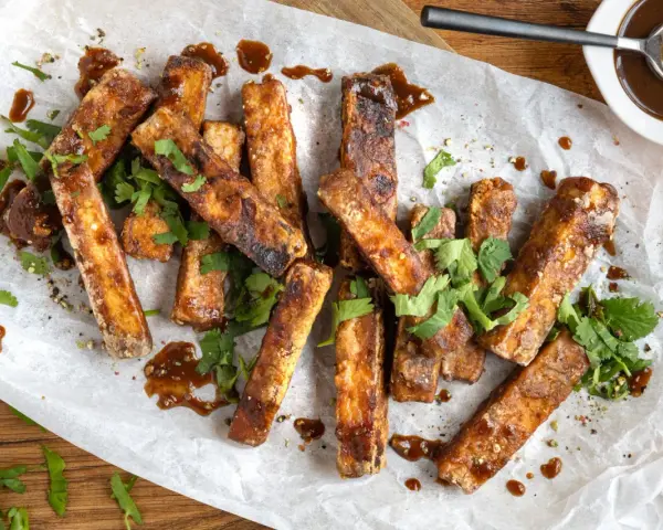 Marinierter Tofu, knusprig gebraten und mit einer dunklen Sauce beträufelt, garniert mit frischem Koriander. Perfekt zum Dippen!