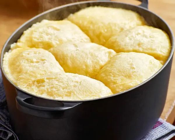 Frisch gebackene Dampfnudeln in einem schwarzen Topf. Ein köstliches Dampfnudel Rezept, das du unbedingt ausprobieren musst!
