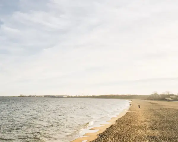 Spokojny dzień nad morzem na Kaszubach. Pusta plaża, delikatne fale i kilka osób spacerujących brzegiem.