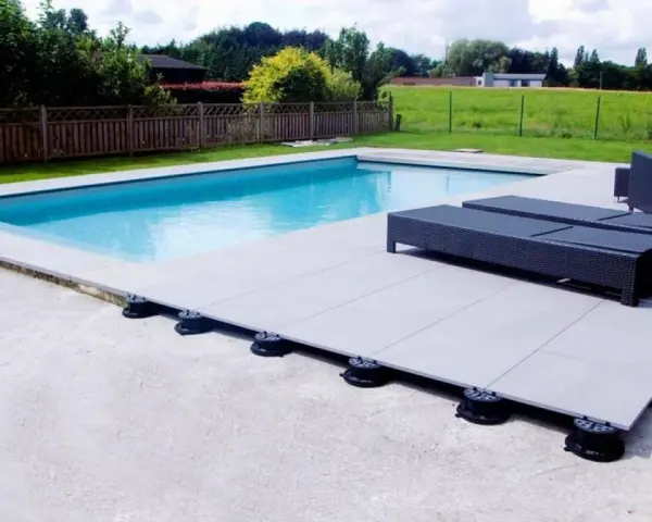 Terrasse de piscine avec dalles sur plots réglables. Le prix au m2 pour ce type de pose est compétitif pour un rendu moderne et pratique.
