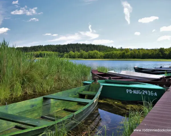 Zielone łodzie przy pomoście, idealne na wyprawę po jeziorach. Suwalszczyzna atrakcje czekają!