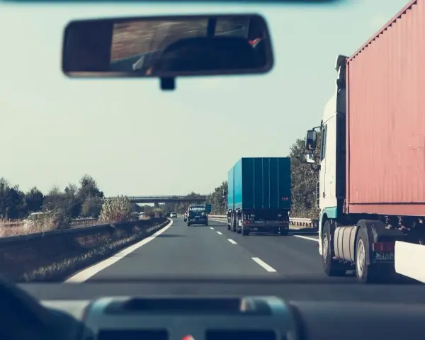 Jadąc autostradą, zastanawiam się, jakie kraje obejmuje zielona karta ubezpieczenia. W lusterku widzę inne ciężarówki.