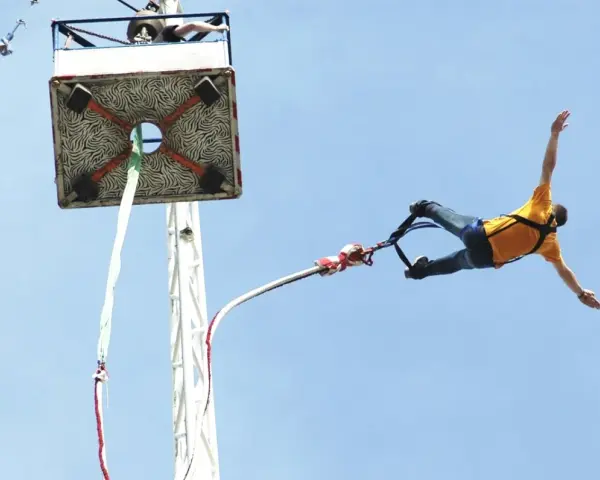 Mężczyzna w żółtej koszulce skacze na bungee. Zastanawiasz się, ile kosztuje skok na bungee?