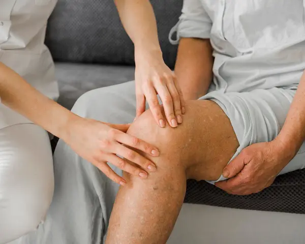 Fizjoterapeuta bada kolano pacjenta po usunięciu łąkotki, przygotowując go do powrotu do sportu.