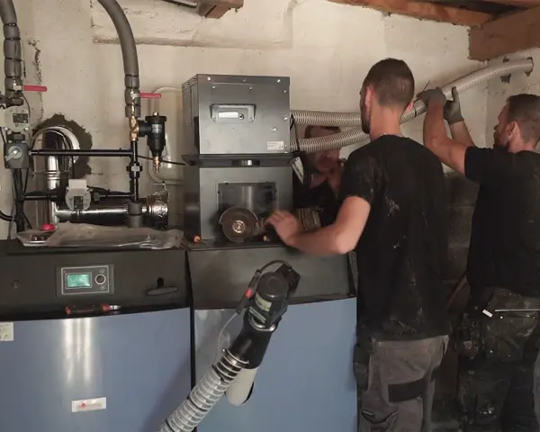 Techniciens installant une nouvelle chaudière, remplaçant une ancienne chaudière fioul. Travaux de chauffage en cours.