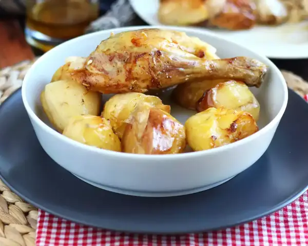 Un invitante pollo al forno con patate dorate, un classico piatto che profuma di casa.