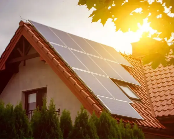 Panele słoneczne na dachu domu. To przykład, jak działa prosument, produkując własną energię.