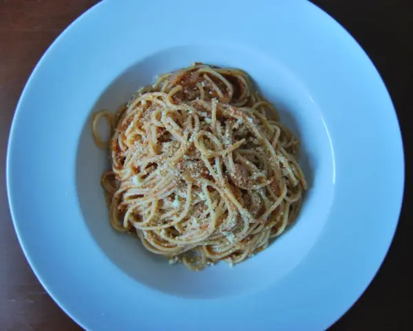 Spaghetti Napoli z sosem pomidorowym i parmezanem, podane w białej głębokiej misce.