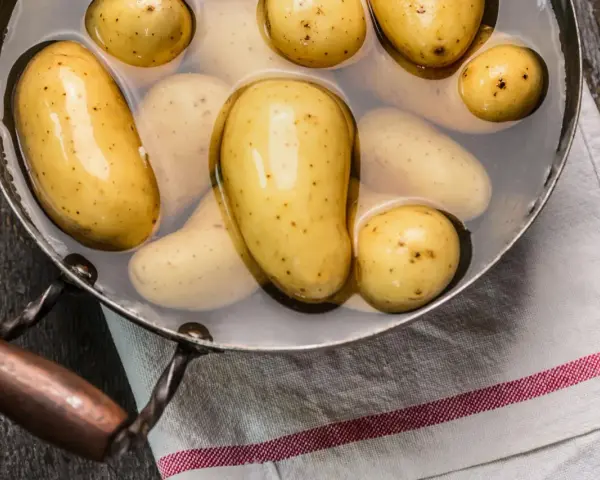 Kleine, gelbe Kartoffeln liegen in Wasser in einem Topf. Sie sind bereit, um sie zu kochen.