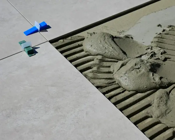 Płytki ceramiczne układane na kleju, widoczne kliny dystansowe i precyzyjnie określona szerokość fugi.