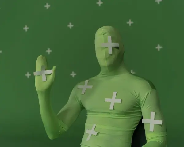 Persona in tuta verde con croci bianche, pronta per effetti speciali. Ecco come si usa il green screen per trasformare la realtà.