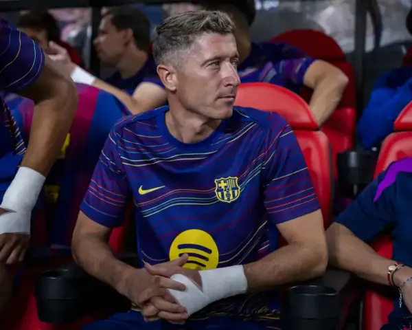Robert Lewandowski w meczu FC Barcelona – Valencia CF, siedzi na ławce z bandażem na ręce, skupiony na grze.
