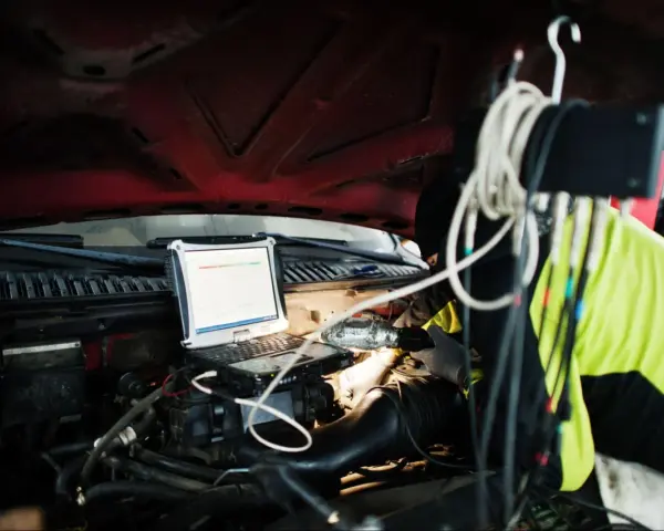 Mechanik diagnozuje problem DTC P0606 Renault za pomocą laptopa pod maską.