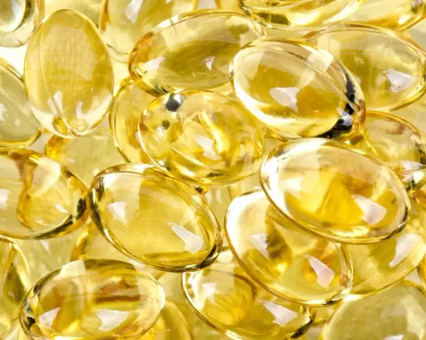 En hög med genomskinliga, gulaktiga kapslar som liknar solens strålar. Dessa kan vara vitaminer som ger energi.