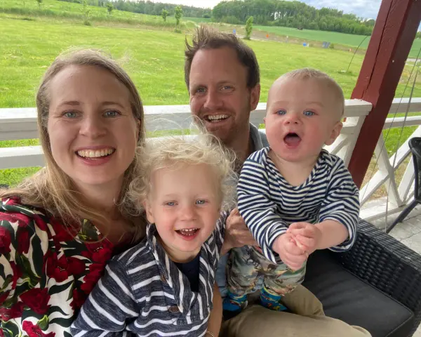 Familj med barn på en altan med grönskande landskap i bakgrunden. En härlig stund med norge med barn.
