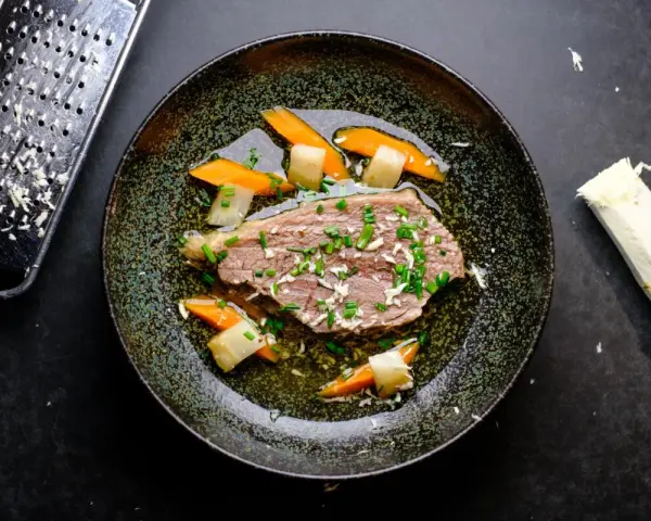 Zarter Tafelspitz braten im Topf, serviert mit Karotten und Lauch. Frisch geriebener Meerrettich daneben.