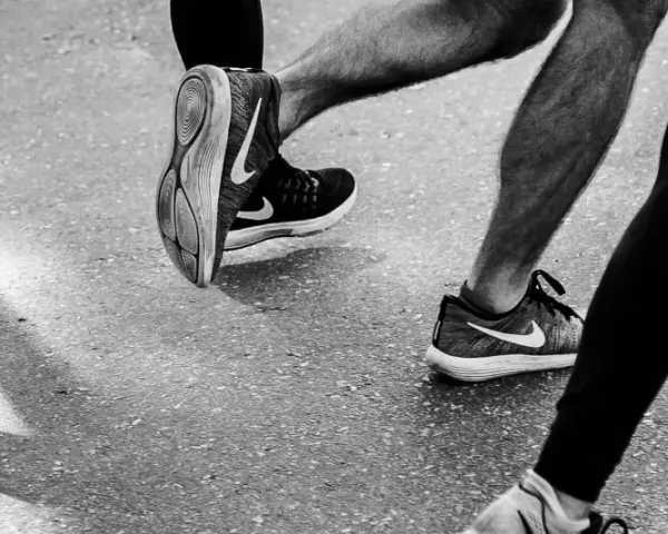 Gambe di corridori in azione, con particolare attenzione al consumo delle scarpe sportive Nike.