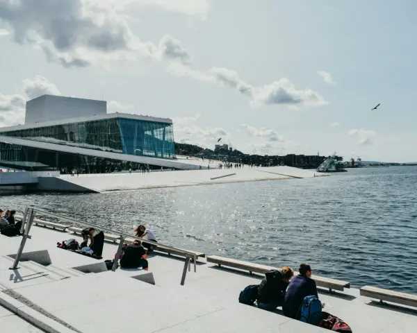 Oslo fiordy jak dojechać: nowoczesna Opera Narodowa i ludzie odpoczywający nad wodą.