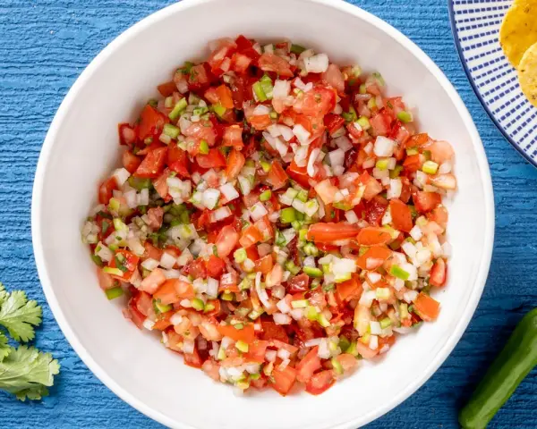 Pico de gallo ricetta: pomodori, cipolla, peperoncino e coriandolo freschi, pronti per essere gustati con nachos.