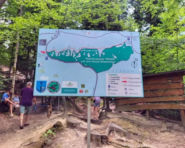 Mapa szlaku w rezerwacie przyrody "Prządki" im. prof. Henryka Świdzińskiego. Turyści z psem zwiedzają malowniczą okolicę.