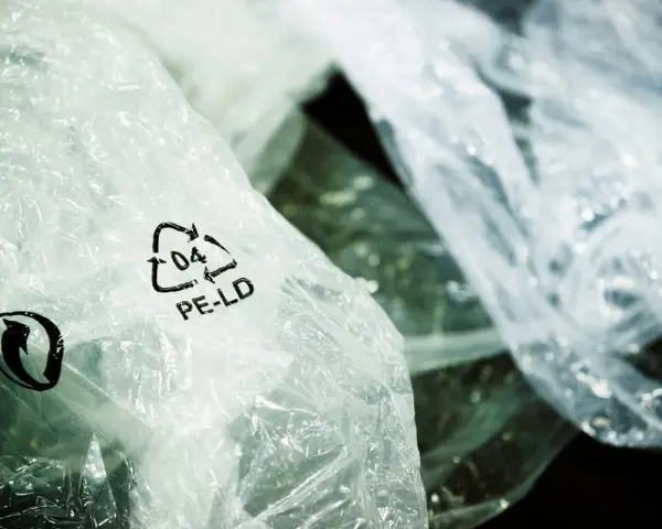 Zgniecione folie PE-LD z symbolem recyklingu. Firma stawia na recykling tworzyw sztucznych, dbając o środowisko.