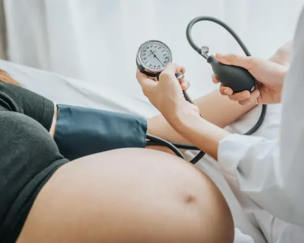 Kobieta w ciąży ma mierzone ciśnienie. Monitorowanie ciśnienia jest kluczowe, by uniknąć powikłań, takich jak wysokie ciśnienie w ciąży.