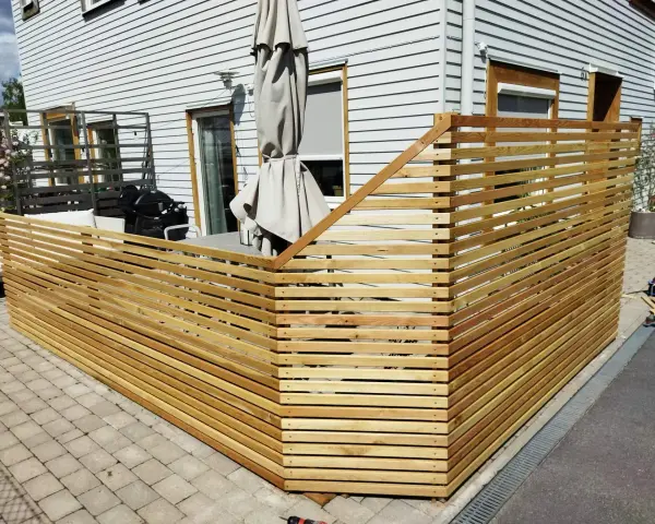 Ett modernt staket i trä som ramar in en uteplats. Perfekt för dig som vill bygga billigt staket och skapa en mysig vrå.