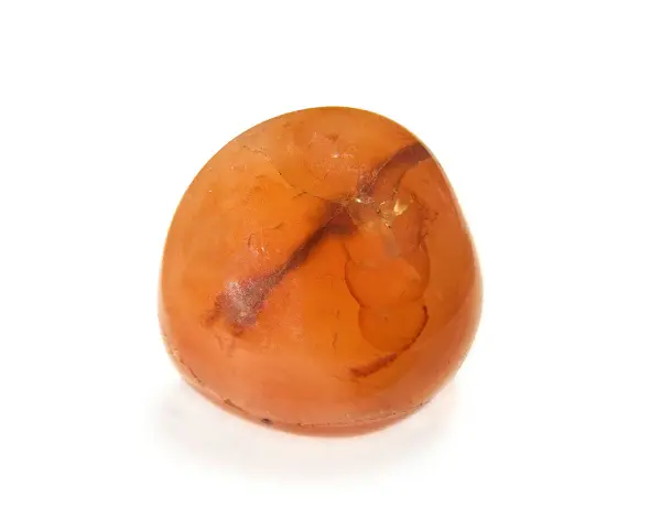Gładki, pomarańczowy kamień z ciemniejszymi żyłkami na białym tle.