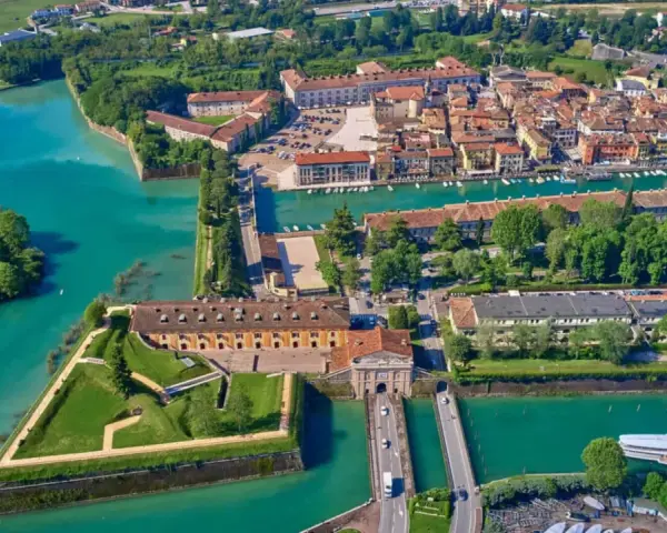Peschiera del Garda centro storico: fortezza a stella circondata da acque turchesi, con edifici storici e un ponte.