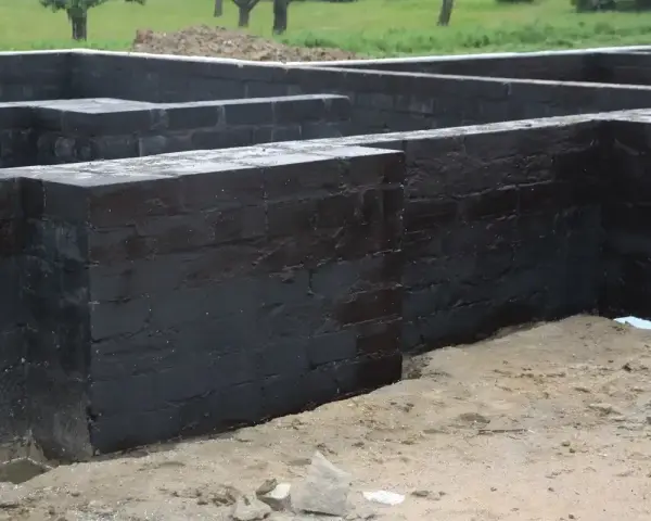 Fundament betonowy z czarnym abizolem, gotowy na kolejne etapy budowy.