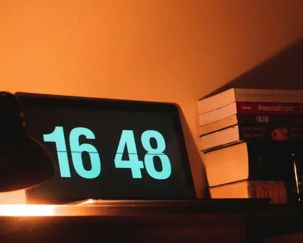 Na ekranie laptopa 16:48. Obok stos książek, w tym "#socialholic". Ile przerwy na 12 godzin pracy?