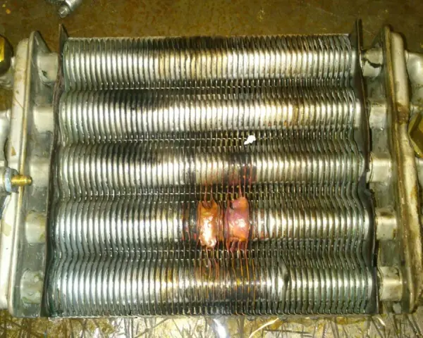 Scambiatore caldaia con evidenti segni di bruciatura, causa rottura scambiatore caldaia. Componenti metallici corrosi e deformati.