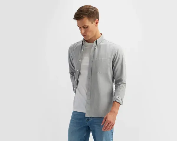 Mężczyzna w szarej koszuli i białej koszulce, prezentujący styl smart casual męski.