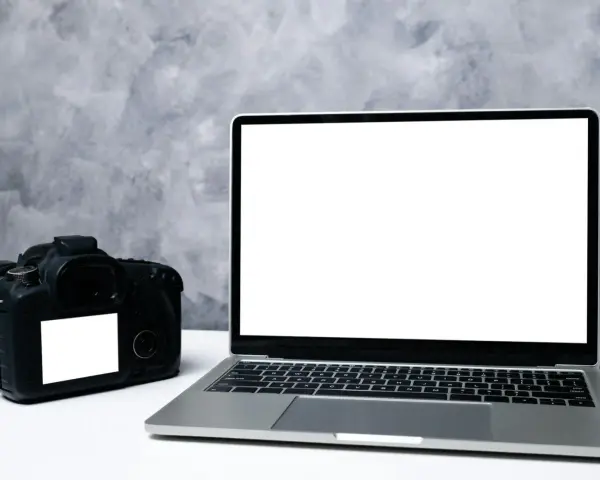 Aparat fotograficzny i laptop z pustym ekranem. Idealne do nauki, jak zgrać zdjęcia z aparatu na komputer.